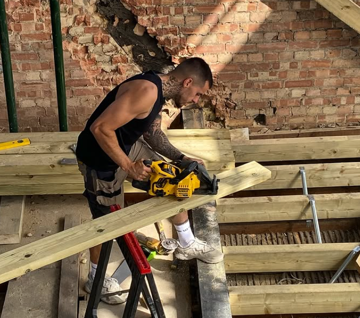 Carpenter cutting timber beams with a circular saw on site